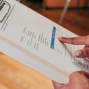 a person pointing at an invoice on a clipboard